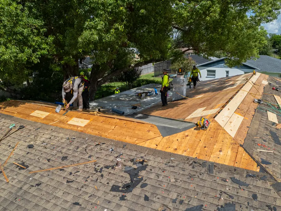 Aerial view of a Gold Key crew laying new plywood decking on a roof after the tear off