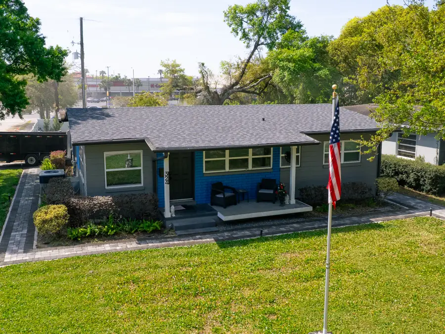 Finished gray architectural shingle roof on a single story home with a blue front porch, seen from the air