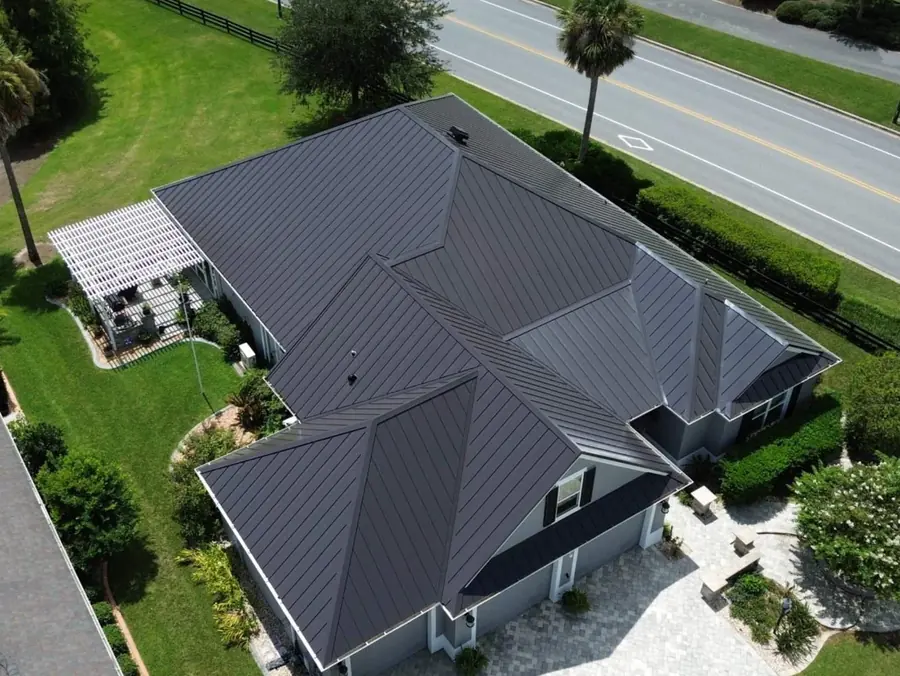 Dark standing seam metal roof on a single story home, seen from the air
