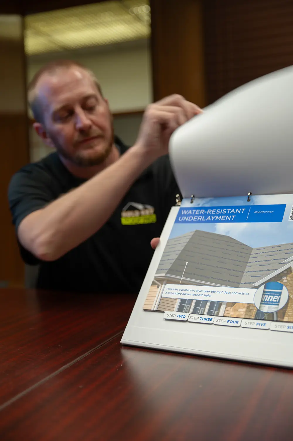 Gold Key team member turning the pages of a roof system guide open to its underlayment page