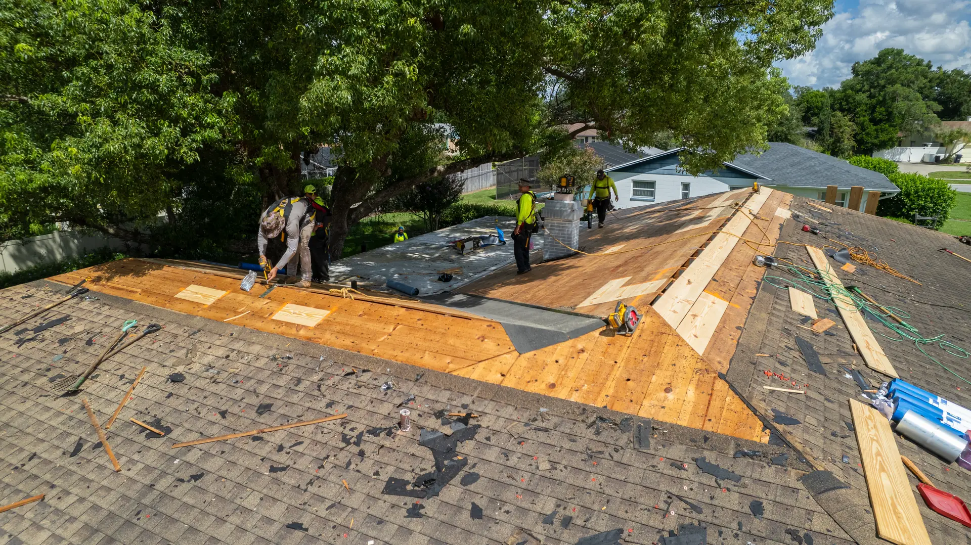 Gold Key crew laying new plywood decking on a roof after the tear off, seen from the air
