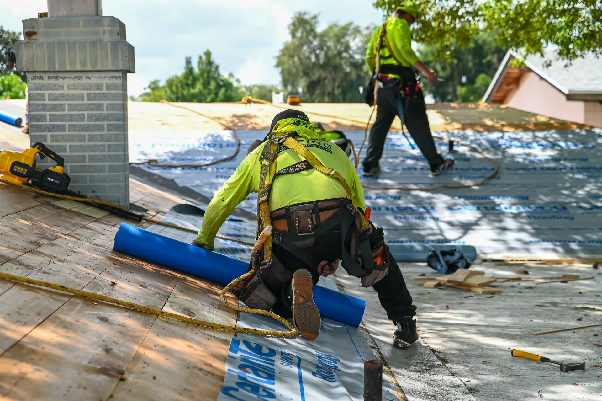 Gold Key roofer laying new underlayment beside a brick chimney on a roof