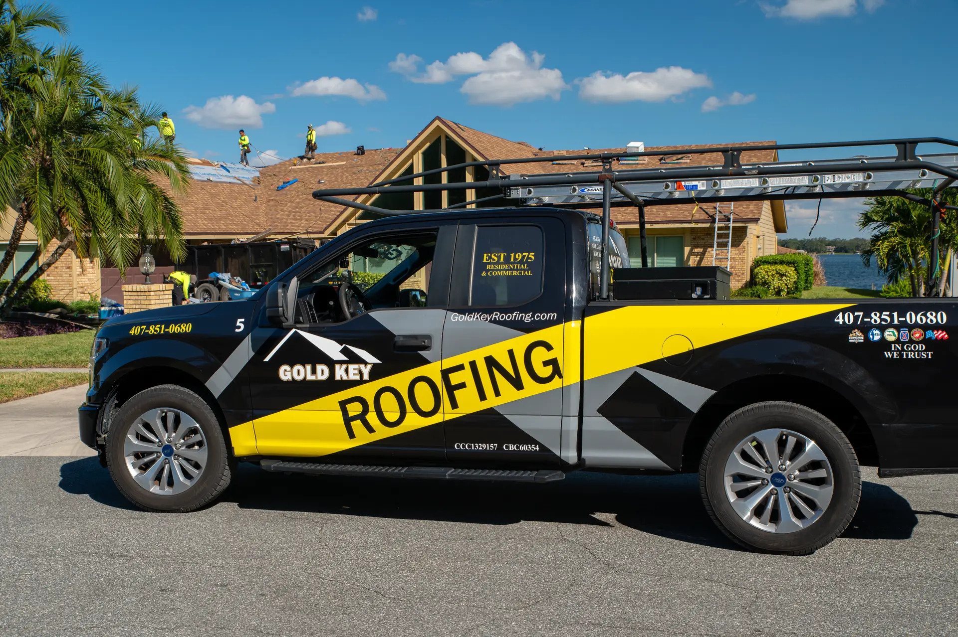 Gold Key Roofing pickup truck parked in front of a home while the crew works on the roof