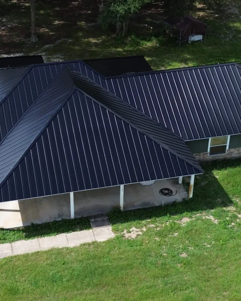 Black standing seam metal roof on a ranch home, seen from above