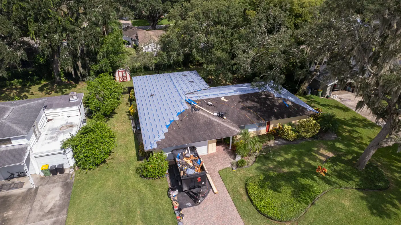 Aerial view of a home with new underlayment going on and a Gold Key trailer in the driveway