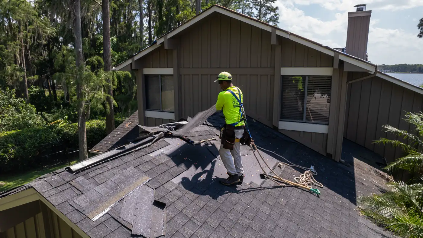 Gold Key roofer on the shingle roof of a house with wood siding beside a lake