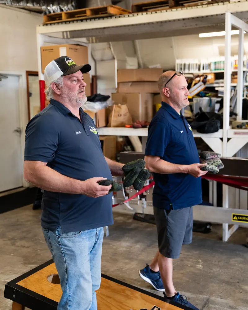 Two team members playing cornhole in the warehouse