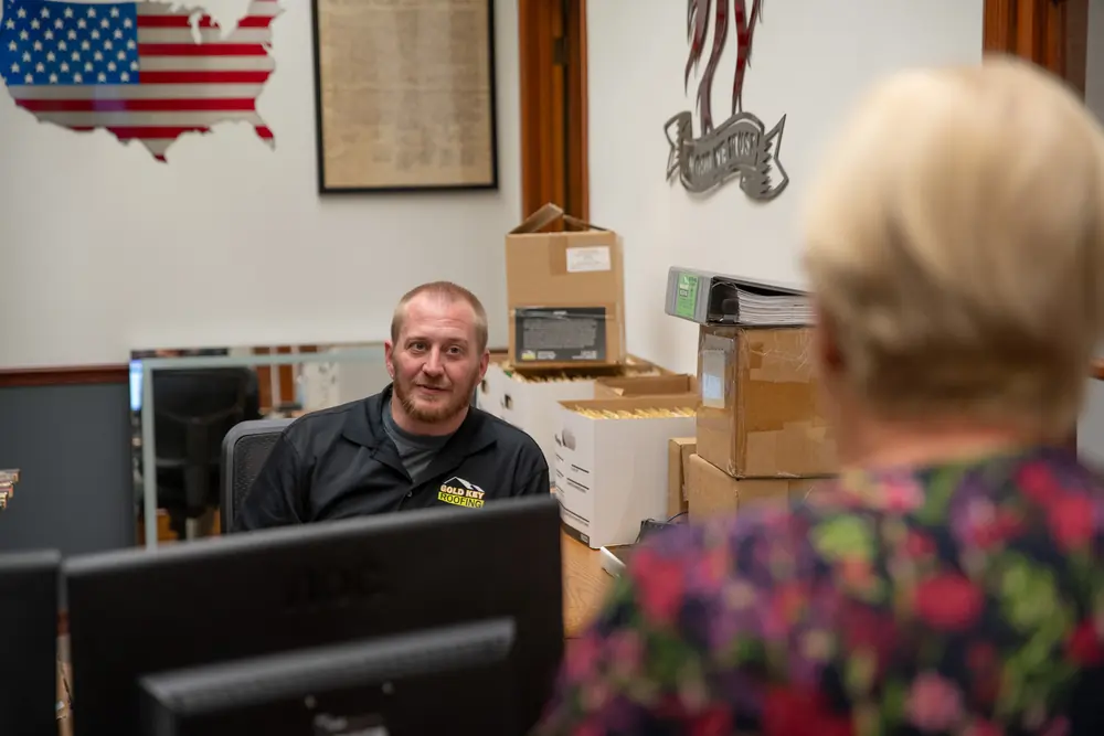 A Gold Key Roofing team member helping a customer at his desk