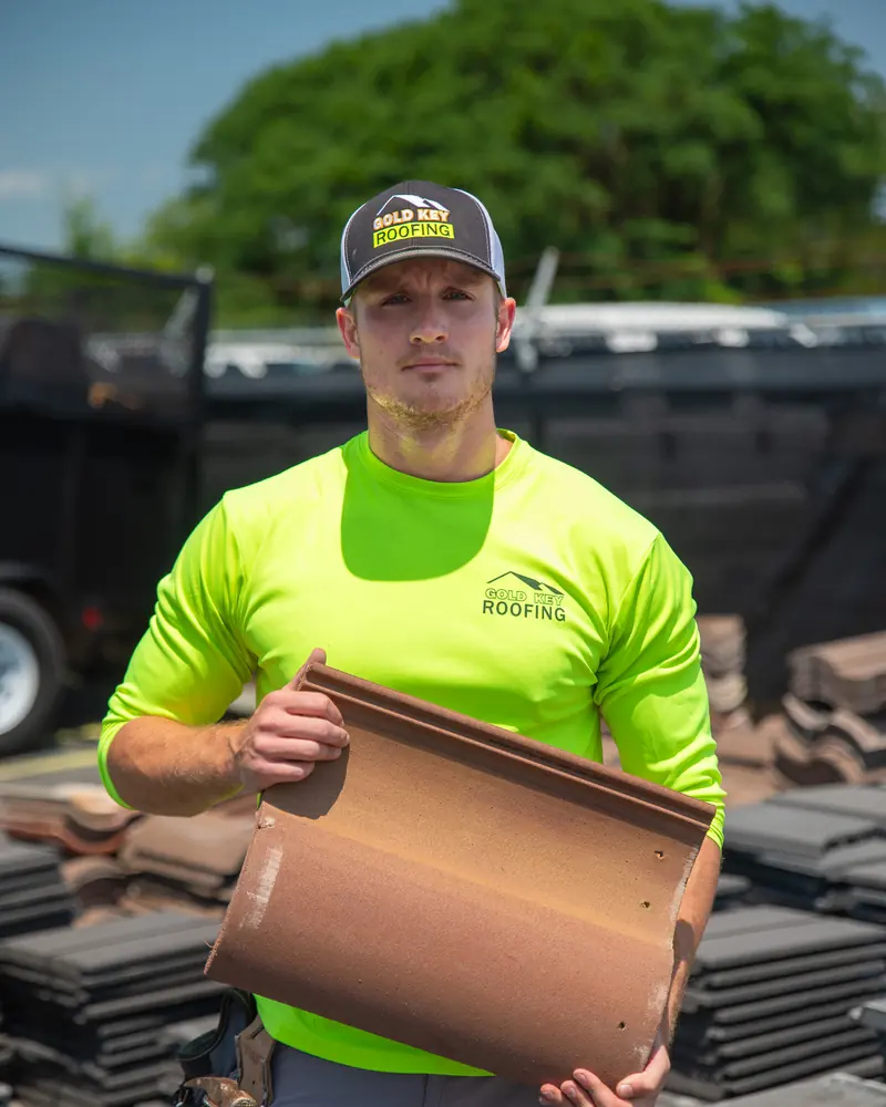 A crew member holding a clay roof tile in the material yard