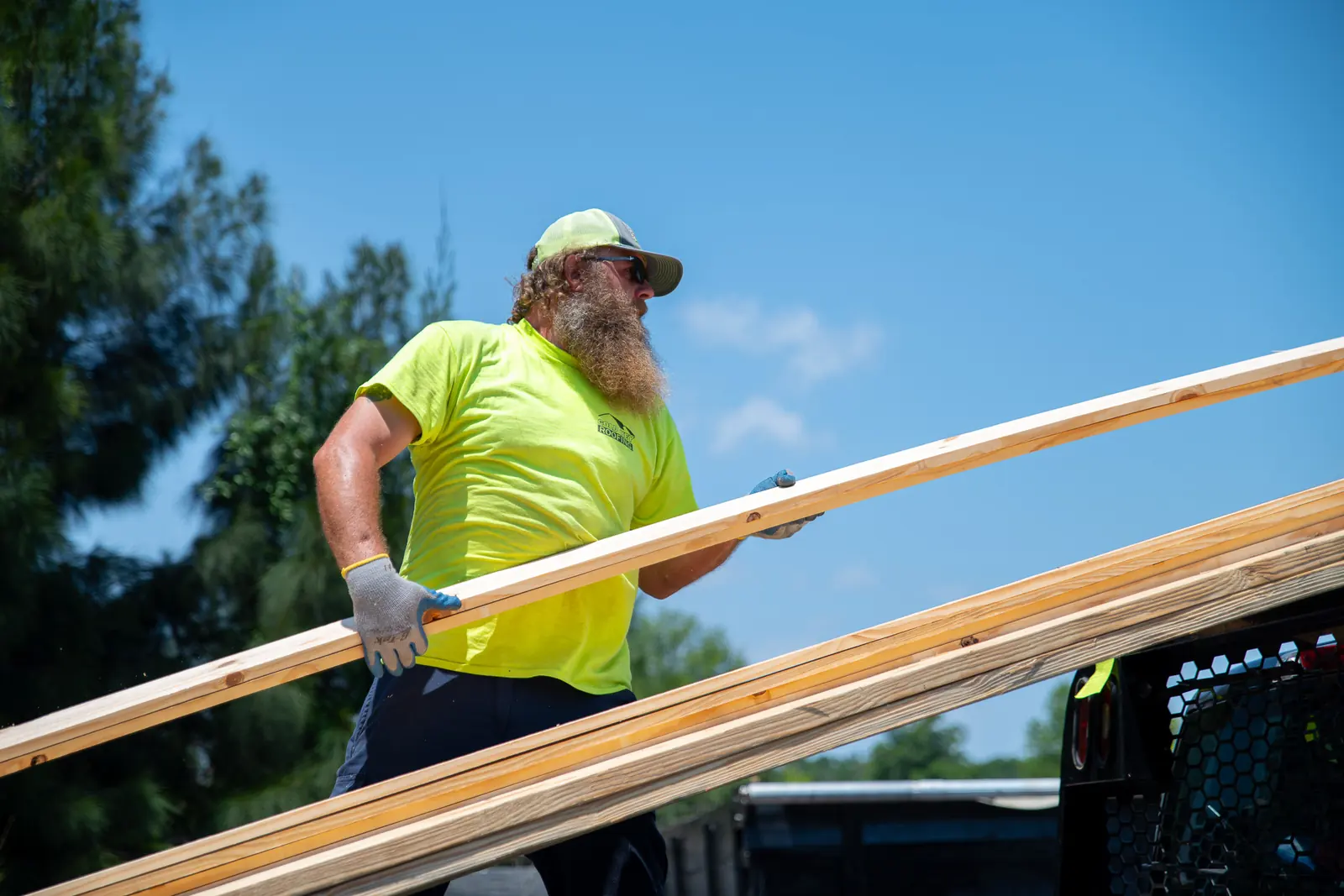A Gold Key Roofing crew member lifting new lumber onto a roof