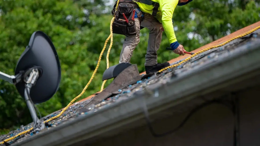 Gold Key Roofing crew member working on a shingle roof with safety equipment